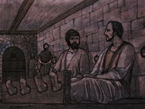 Als er diese Befehle erhielt, sperrte er sie in die innere Zelle und legte ihre Füße in den Block.<br/>Gegen Mitternacht beteten Paulus und Silas und sangen Loblieder auf Gott, und die anderen Gefangenen hörten ihnen zu. – Folie 6